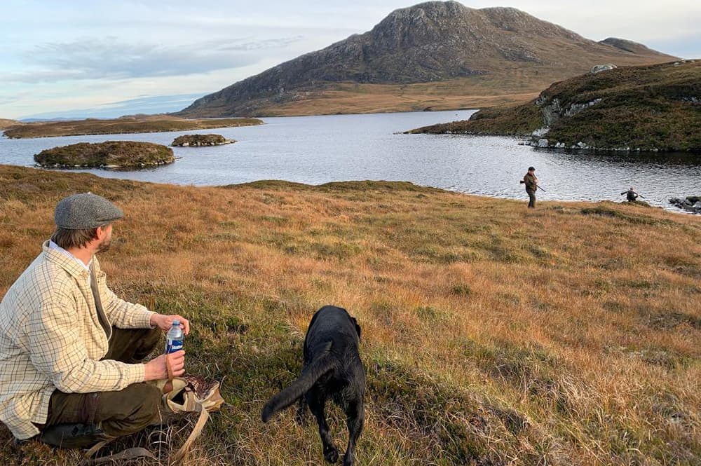A gun resting with his dog above a North Uist loch